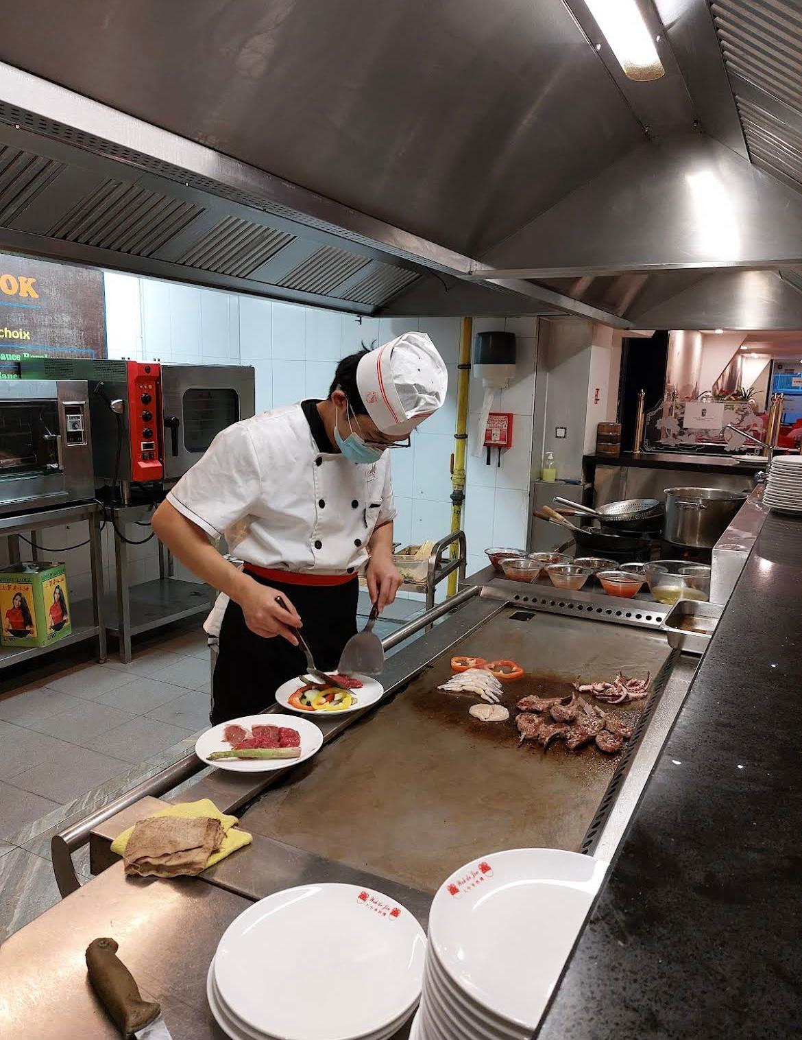 Notre chef prépare des légumes, viandes et fruits de mer au teppanyaki